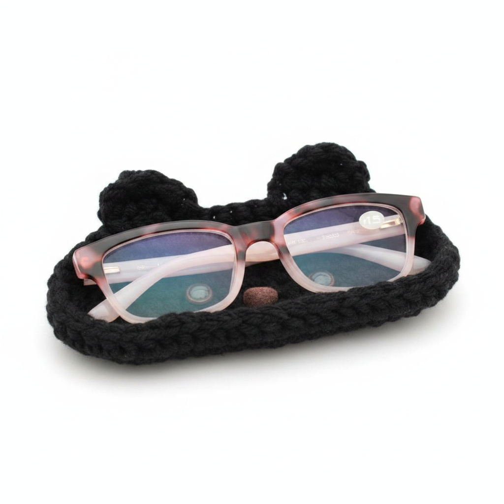 Handcrafted black crochet cat eyeglasses holder with pink tortoiseshell glasses on a clean white background