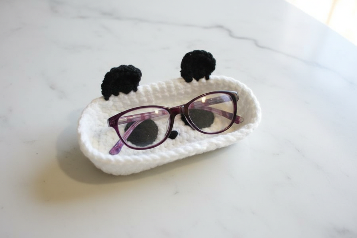 Handmade crochet panda case on white marble with glasses
